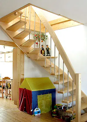 Holztreppe mit Wendung und Stahlstäben im Geländer in einem Wohnraum